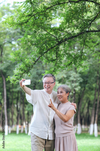 Happy old couple take selfie with mobile phone in park