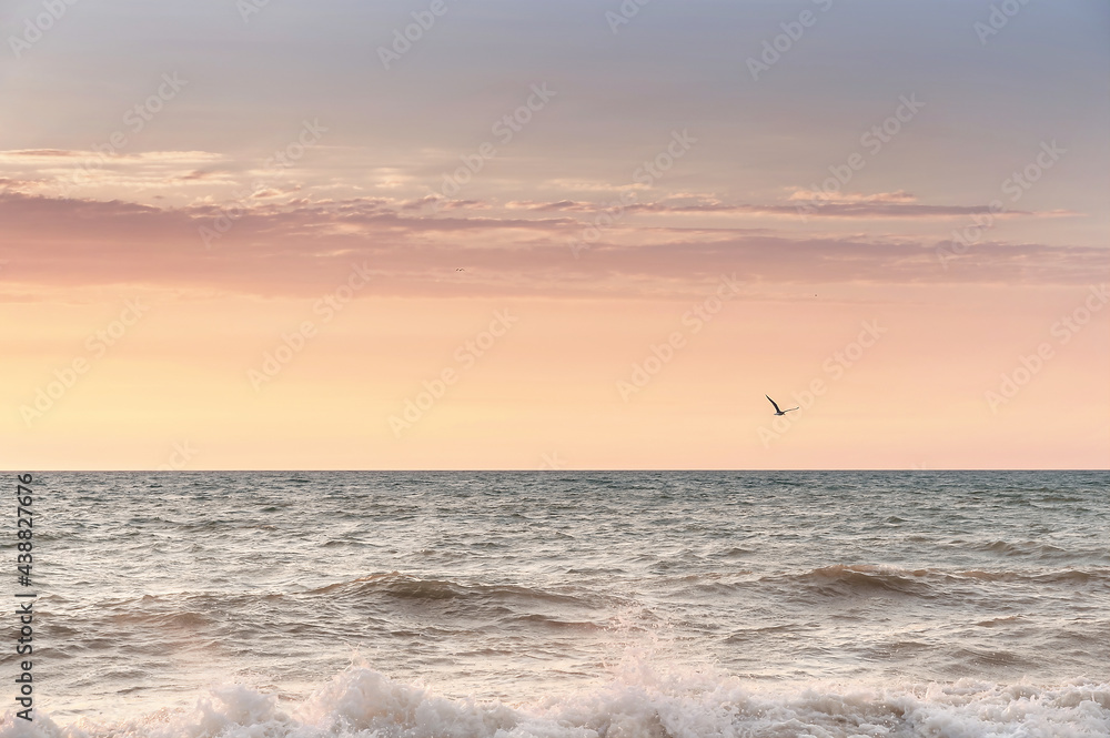 Green blue sea splashing waves backlit by setting sun in front of beautiful sunset sky background. Travel and tourism concept. Nature background. Copy space.
