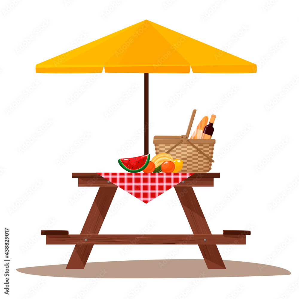 Picnic table with umbrella. Picnic basket with fruit and baguette