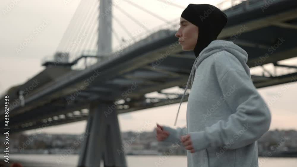Side view of woman in hijab running on riverside Side view of woman in hijab running on riverside
