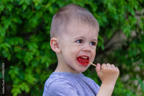 Photo of a boy with a lollipop on a green background. Selective focus