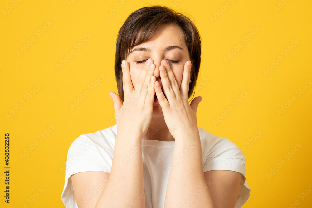 Disappointed dejected female wearing white loose T-shirt covering her face with hands being tired and exhausted. Desperate woman having depression hiding her crying face with hands. Disappointed dejected female wearing white loose T-shirt covering her face with hands being tired and exhausted. Desperate woman having depression hiding her crying face with hands.