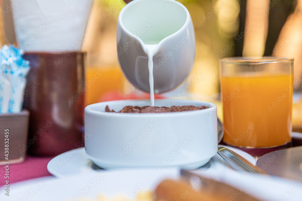 Pouring milk into the bowl with wheat buckwheat bran cereal. Healthy breakfast concept Pouring milk into the bowl with wheat buckwheat bran cereal. Healthy breakfast concept