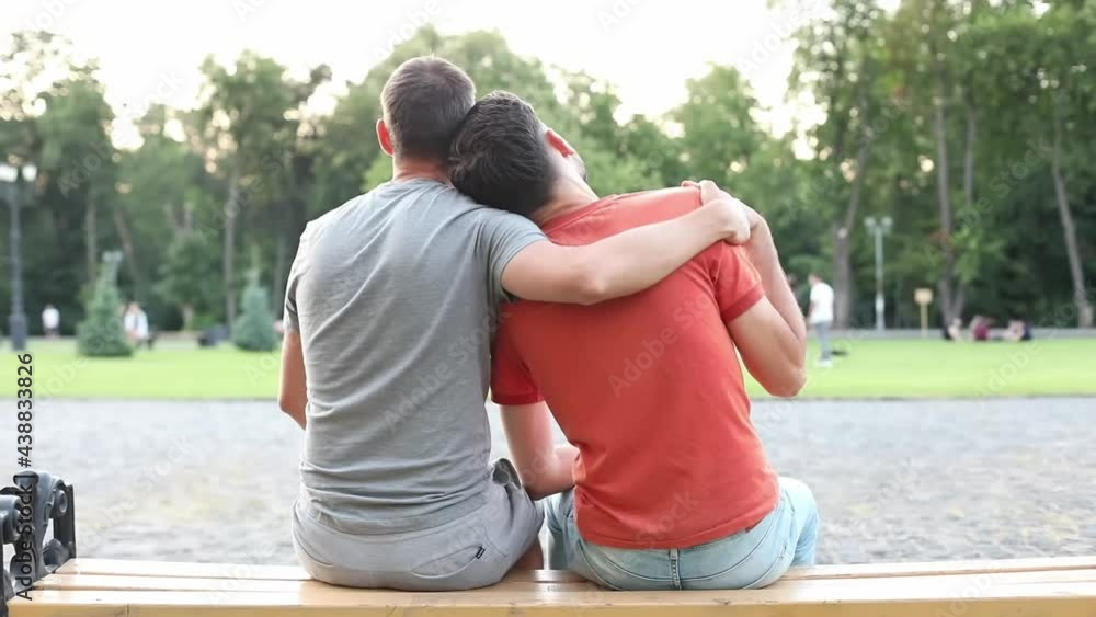 Vid o Stock Young Gay Couple Happy Sitting On Bench In Park Gay Couple 