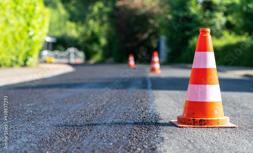 Construction cones marking part of road with a layer of fresh asphalt.