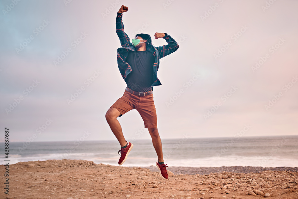 Obraz premium Hombre Joven latino saltando en la arena durante un bello atardecer.. Joven feliz en la playa
