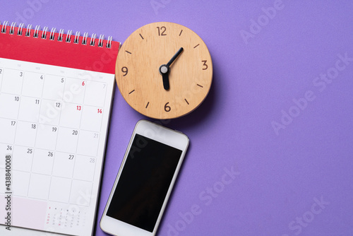 close up of calendar, mobile phone and alaram clock on the purple table background, planning for business meeting or travel planning concept photo