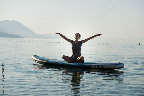 Young woman celebrating life practicing yoga on sup board © Gajus