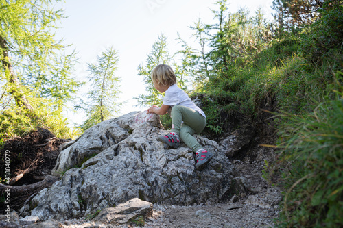 Toddler child climbing the rock on a hiking trail