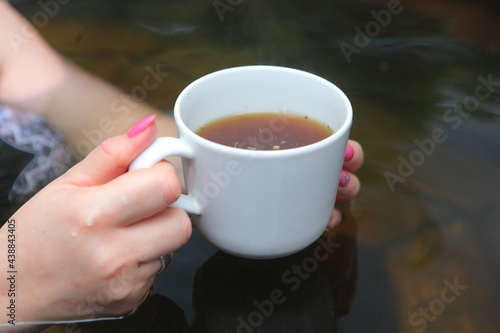 Female hands holding a mug with herbal tea