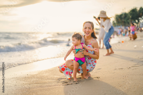 mom and baby in happy time on the beach in evening time with beautiful sunset light and blur tourist background at bangsean beach. Thailand photo