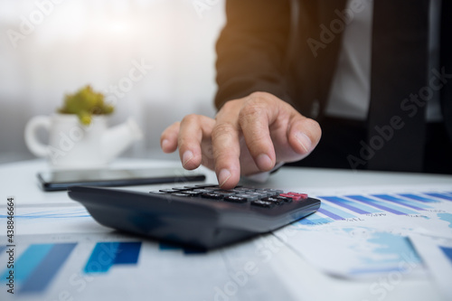 Businessman counting on calculator and reviewing budget on business