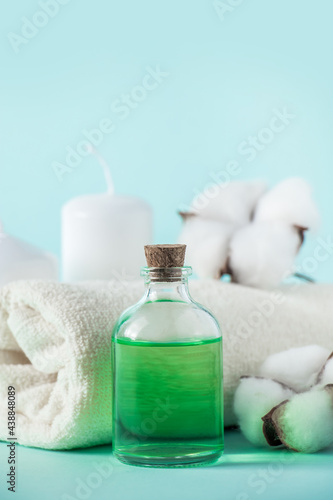 Aromatherapy wellness concept. Spa and relaxation accessories on blue background. Aromatic oil, towel, candle and flowers. Organic skin care product.