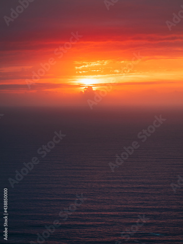 Sun setting behind the clouds on the Atlantic Ocean with very calm sea