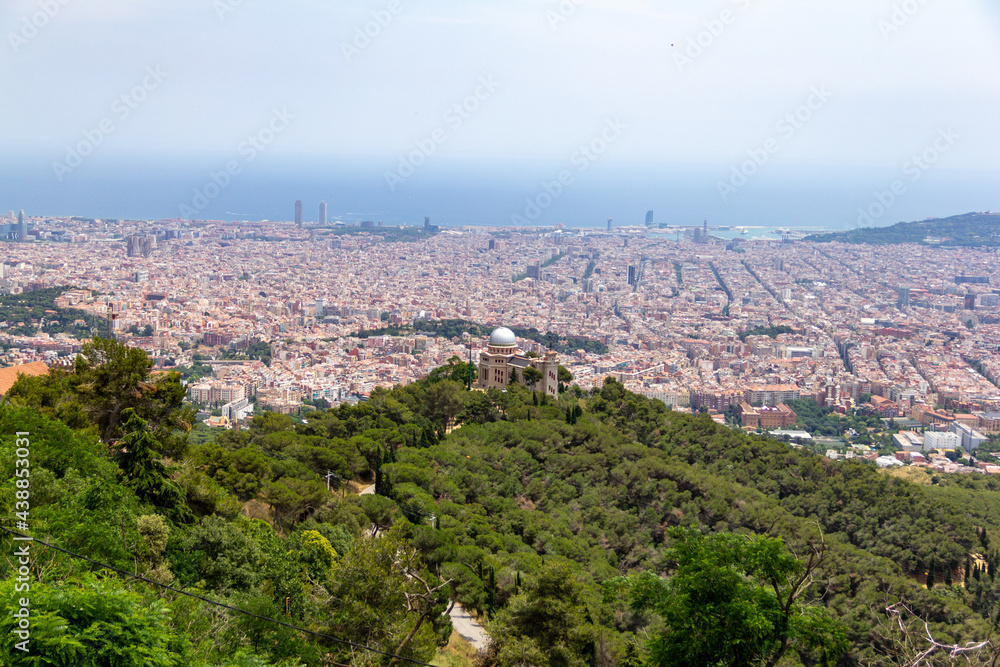 View over Barcelona city from Tibidabo mountain in Spain during summer sunny day, trees, buildings and sea on one shoot.