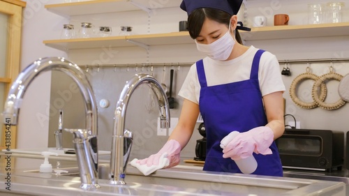 キッチンを清掃して除菌する家事代行のマスクをした女性作業員