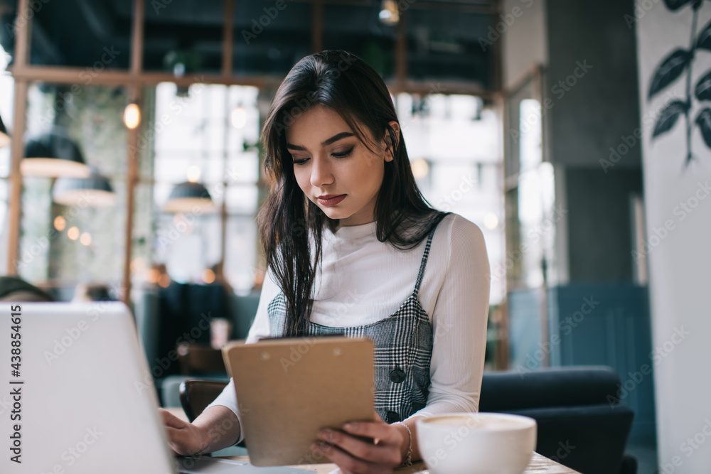 Focused woman with clipboard using laptop Focused woman with clipboard using laptop