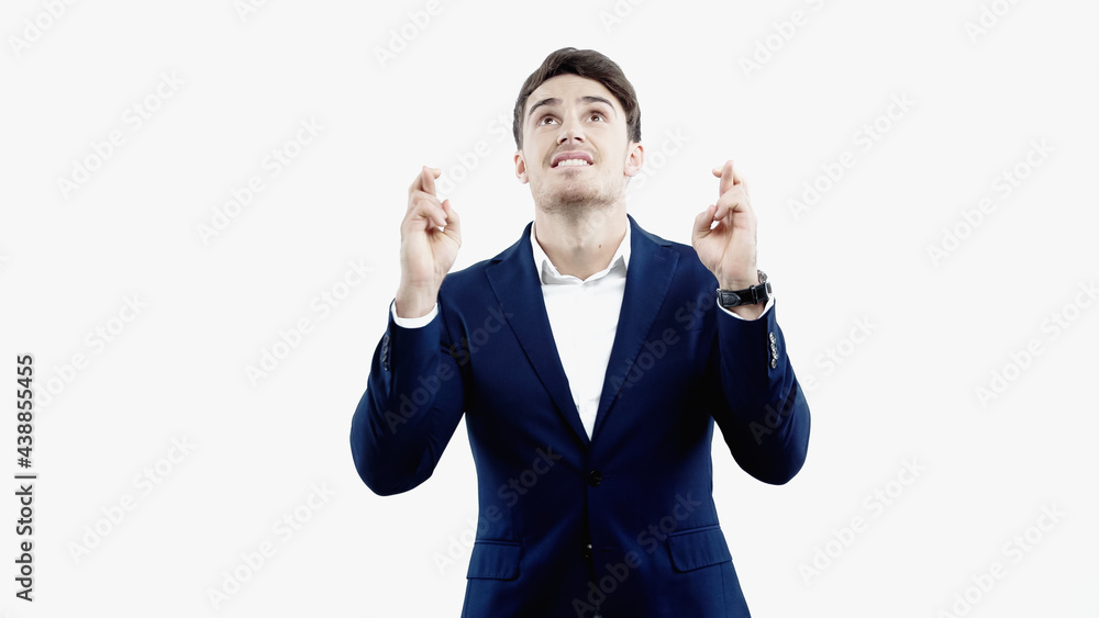 Businessman with crossed fingers looking up isolated on white Businessman with crossed fingers looking up isolated on white