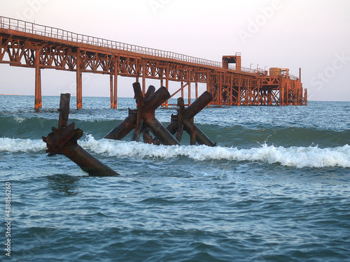 Wallpaper Mural An old iron rusty pier, wharf, a bridge in a blue sea painted in orange color with the rays of the morning sun Torontodigital.ca