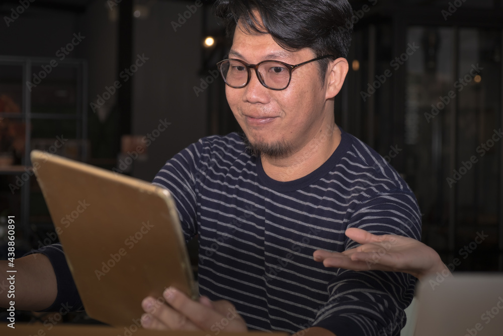 An attractive Asian smart and handsome male face, young adult man with dark hair portrait wear eyes glass and hold the tablet for the concept of high technology working business communication office An attractive Asian smart and handsome male face, young adult man with dark hair portrait wear eyes glass and hold the tablet for the concept of high technology working business communication office