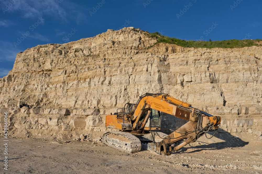Obraz premium Excavator stands on the background of a stone quarry.