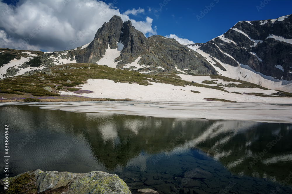 Obraz premium Beautiful spring mountain landscape, Rila Mountain, Seven Rila Lakes, Bulgaria. Frozen glacial lakes against the backdrop of a high rocky peak, meadows with blooming crocuses in the foreground.