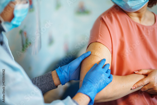 Close up photo of senior patient arm with doctor`s hands making injection. Elderly patient wearing mask to stop coronavirus spread. Covid 19 vaccination. Old people. Elderly virus protection.