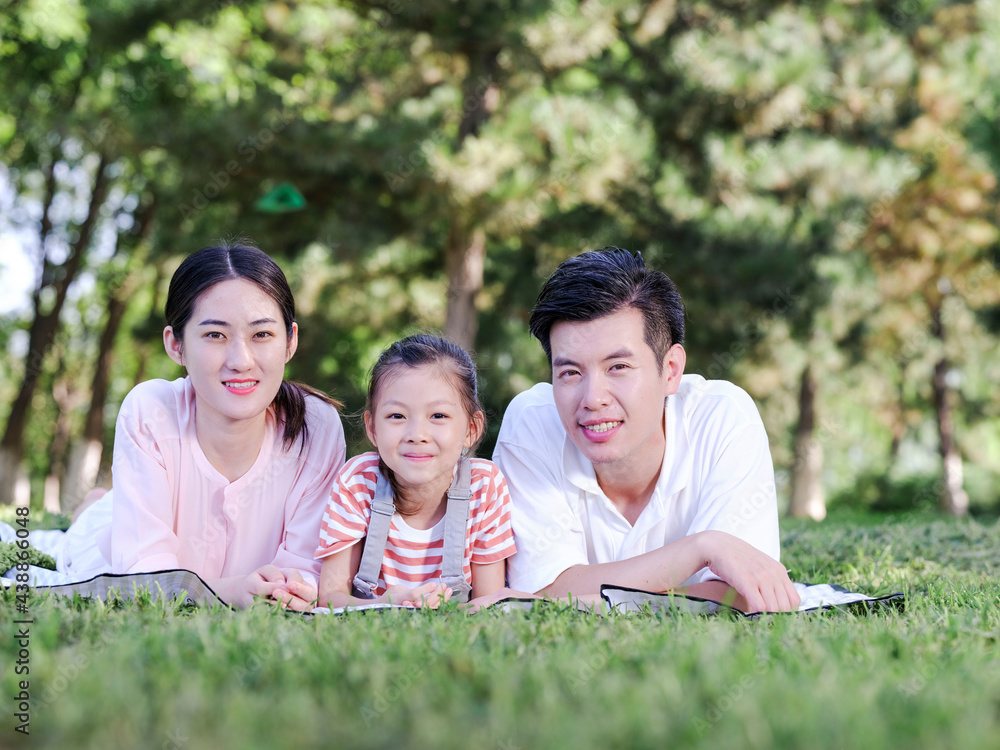 Happy family of three on the park grass