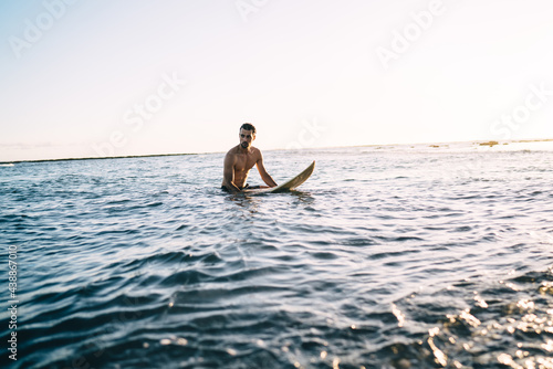 Fotografía Athletic young man with surfboard relaxing in ocean water