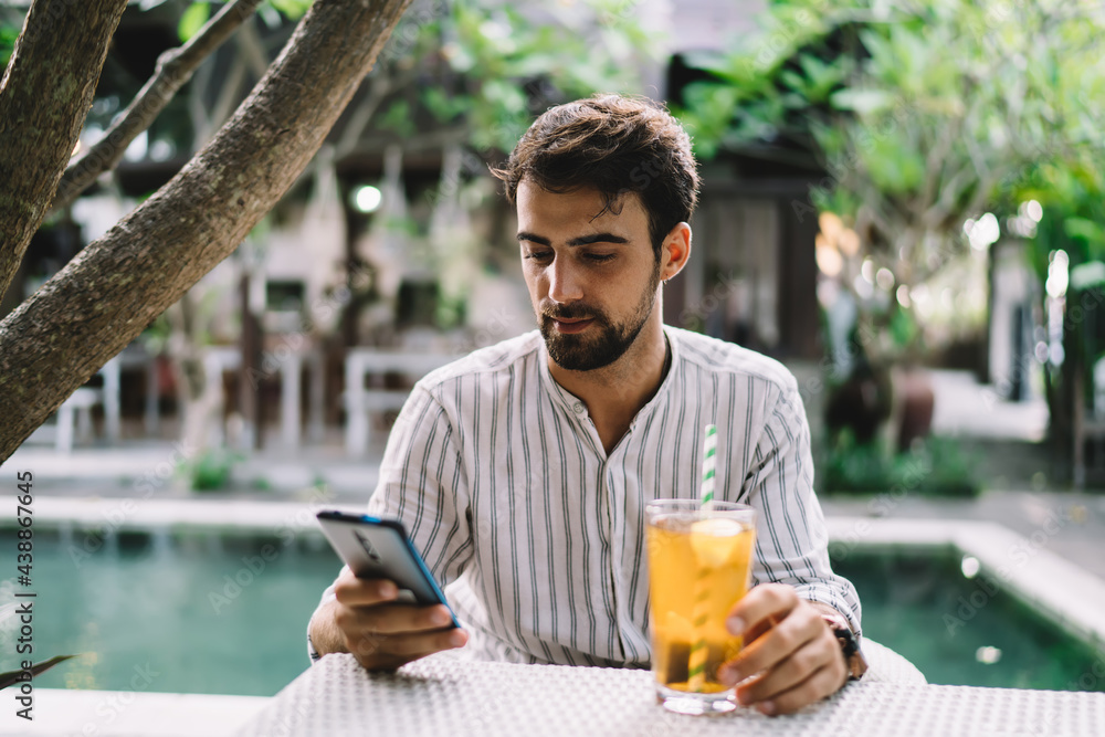 Guy with glass of ice tea chatting on smartphone outdoors Guy with glass of ice tea chatting on smartphone outdoors