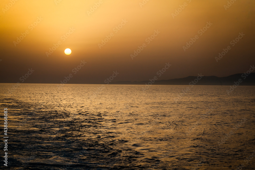 Red-orange sunset on the sea. Red sun on the horizon at sunset on the high seas.