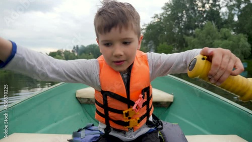 Boy rowing boat children. Kid float on a boat river city holiday. Kid rides a boat with paddle. Child rowing oars on a boat a lake park city. Recreation children's camp during holidays on the river