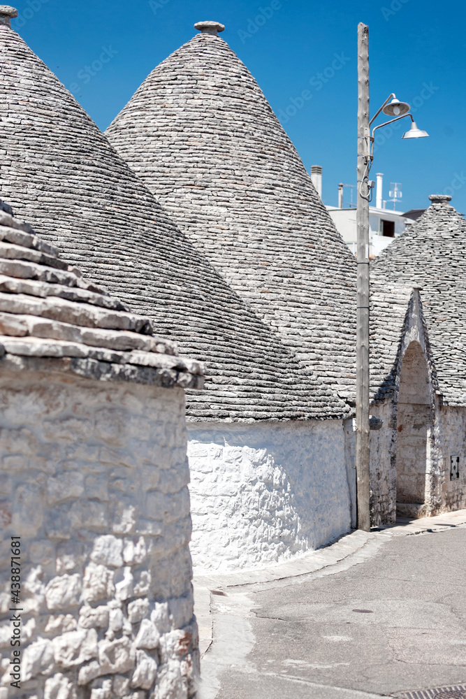 Alberobello, Puglia, Brindisi, Italy - july 19, 2017: View of the Famous village with typical dry stone Trulli houses and conical roof. Trulli picturesque street in the old town. Cone-roofed houses