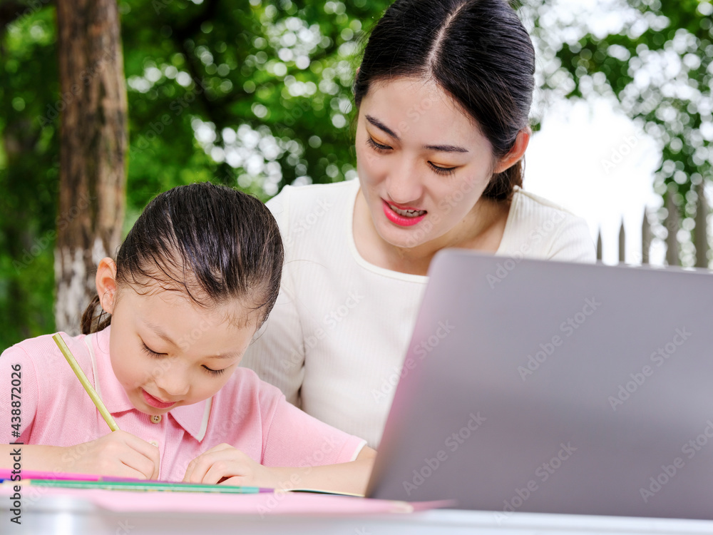 Young mothers help their children with their homework Young mothers help their children with their homework