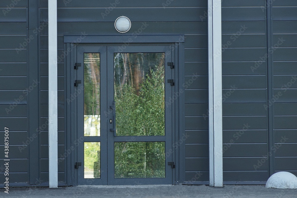 one closed glass door on a black iron wall of a building on the street one closed glass door on a black iron wall of a building on the street