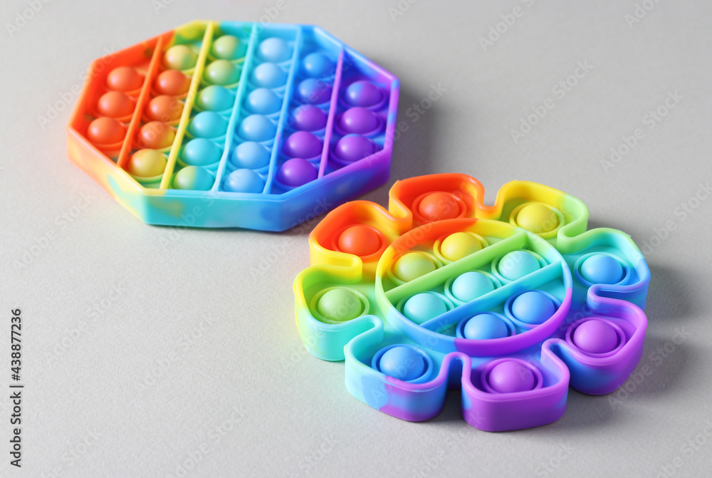 Two popular silicone colorful antistress pop it toys for child on light background. Simple dimple. Close-up Two popular silicone colorful antistress pop it toys for child on light background. Simple dimple. Close-up