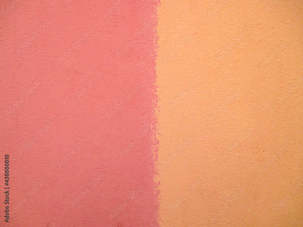 Fototapeta premium Background from the wall in pink and yellow. The texture is unevenly colored, rough, matte, a lot of smudges. The space is divided into two halves by color.