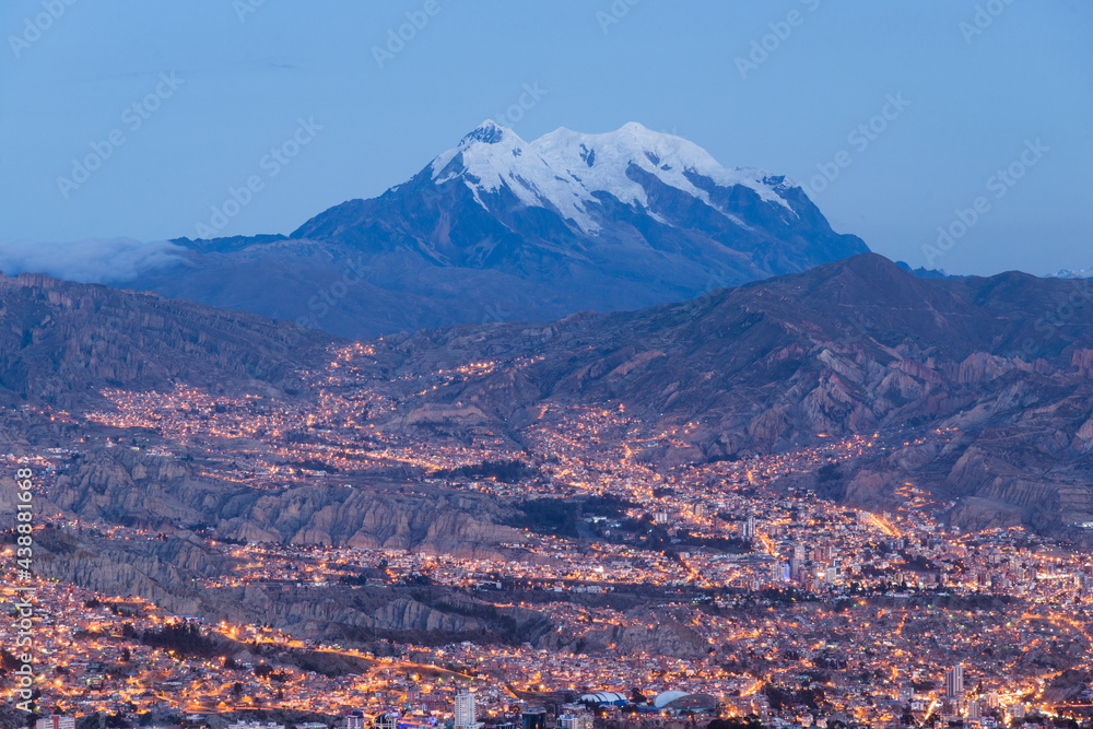 Cidade de La Paz no início da noite e ao fundo o cume nevado do Ilimani, montanha que domina a paisagem. Cordilheira dos Andes, Bolívia 