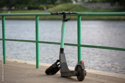 Broken electric scooter abandoned on river promenade in the city