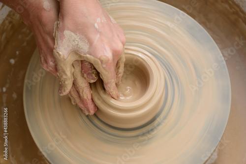 Hands working with clay on potter's wheel. Clay molding process