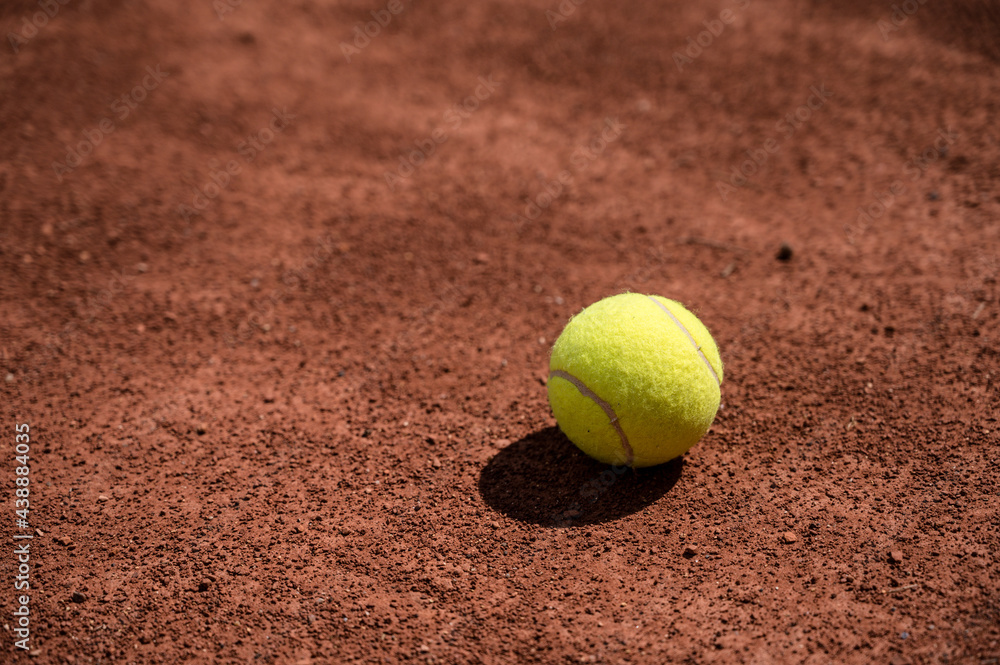 Close-up of yellow tennis ball on clay tennis court. Sport. Lifestyle.