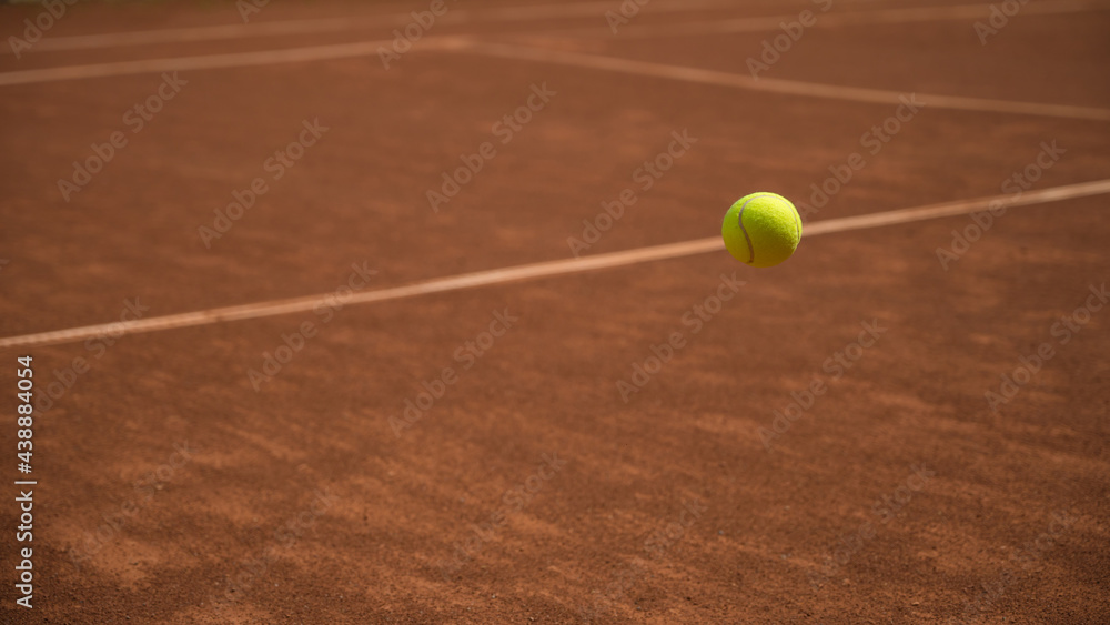 Yellow tennis ball in motion fluing under clay tennis court. Process of game. Sport. Lifestyle.