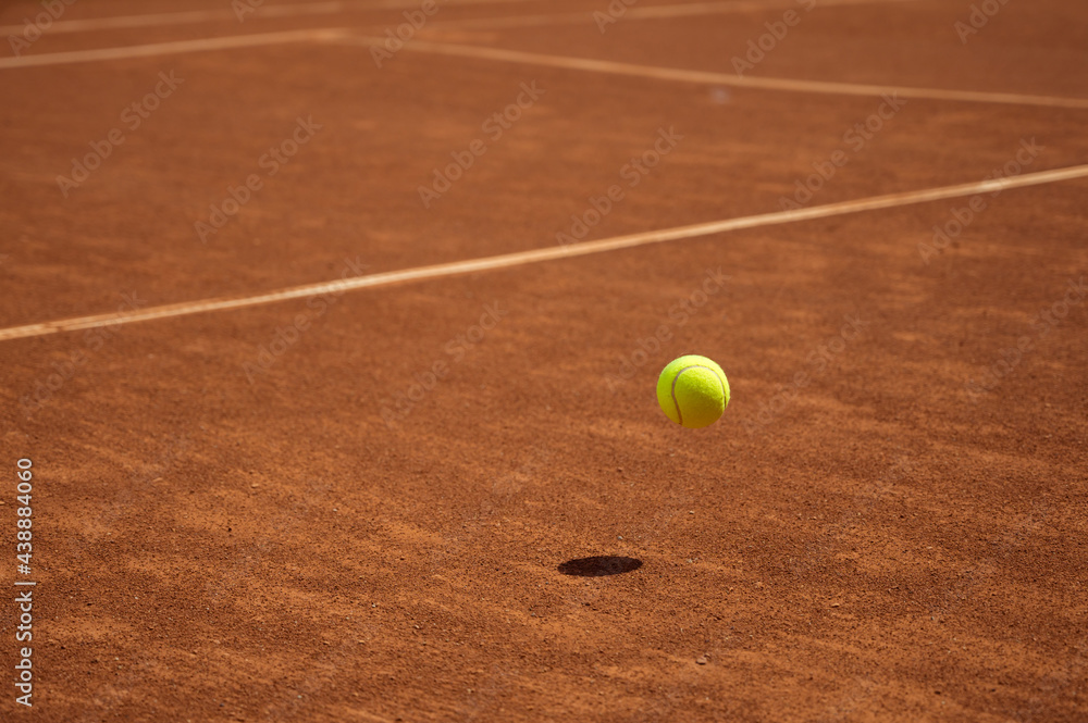 Yellow tennis ball in motion fluing under clay tennis court. Process of game. Sport. Lifestyle.