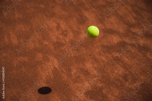 Yellow tennis ball in motion fluing under clay tennis court. Process of game. Sport. Lifestyle.