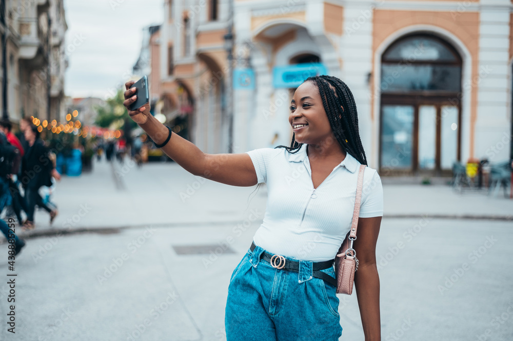 Cheerful african american woman taking selfie with her smartphone