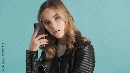 Tired blond teenager girl looking bored holding smartphone waiti photo