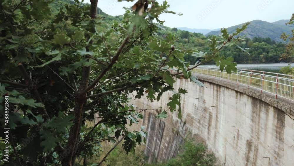 Arched concrete bridge on a dam built between two mountain ridges covered with forest Arched concrete bridge on a dam built between two mountain ridges covered with forest