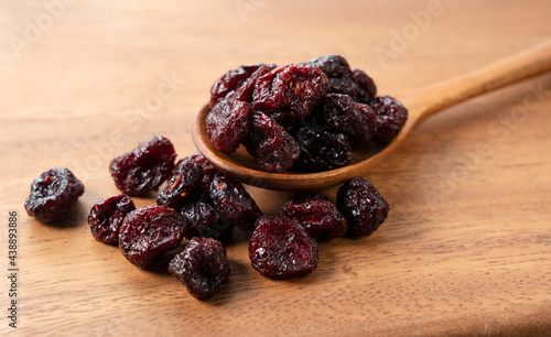 Dried cranberries with a wooden spoon on a wooden background.