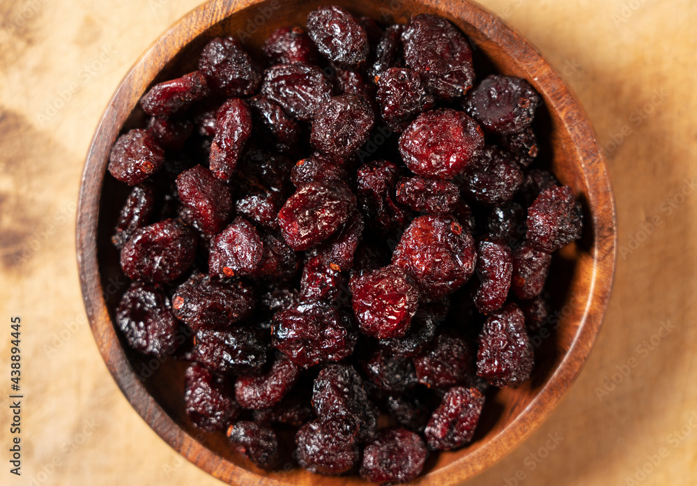 Dried cranberries in a wooden bowl on a wooden background. Dried cranberries in a wooden bowl on a wooden background.