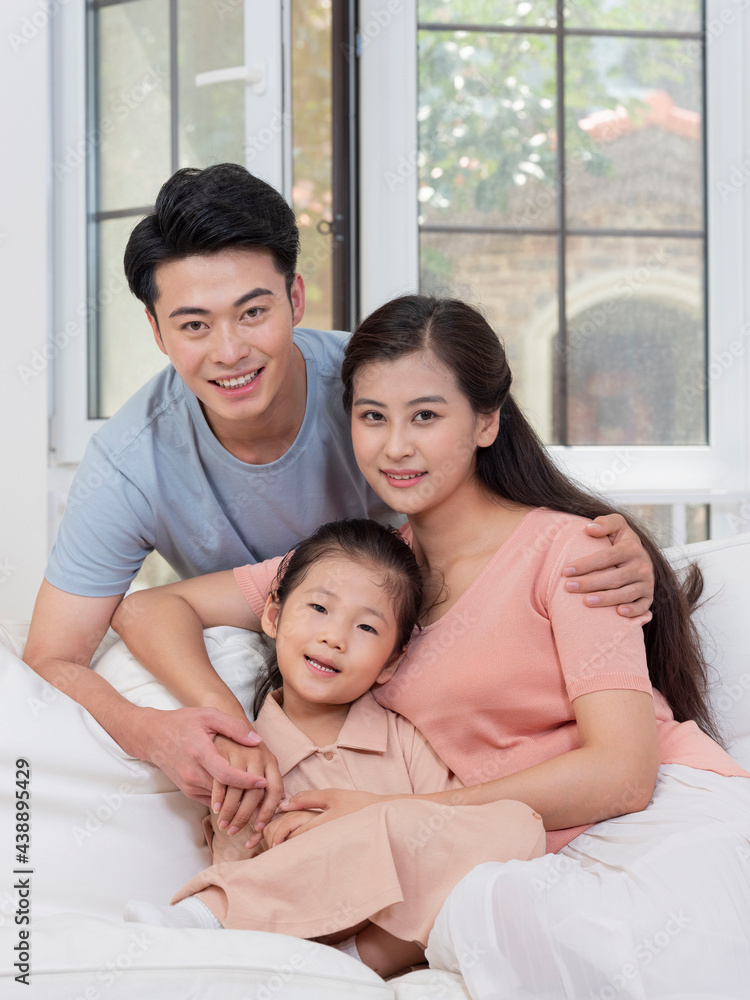 A happy family of three is sitting on the sofa in the living room A happy family of three is sitting on the sofa in the living room